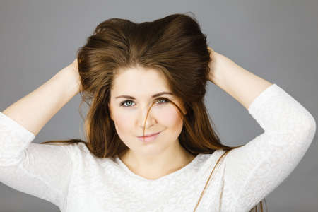 Happy positive woman with long brown hair presenting her healthy hairdo. Haircare concept. Studio...