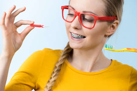 Dentist and orthodontist concept. Young woman smiling cleaning and brushing teeth with braces using toothbrushの写真素材