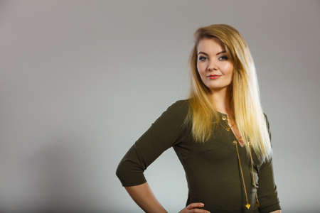 Fashionable outfit ideas, trendy clothes concept. Attractive blonde woman wearing tight dark green khaki topの写真素材