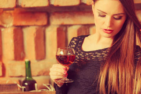 Elegant beauty lady long hair full make up wearing black dress tasting wine in rural cottage interior cellerの写真素材