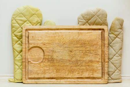 Home interior objects concept. Detailed top view closeup of old fashioned wooden kitchen board and glovesの写真素材