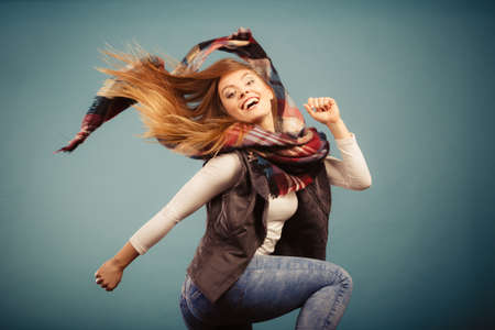 Autumnal outfit concept. Joyful female wearing warm autumn clothing having fun, jumping and dancingの写真素材