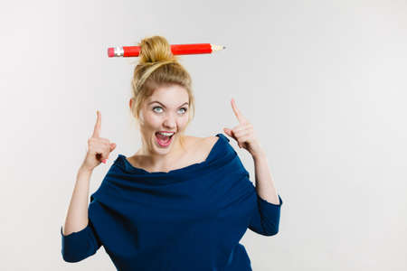 Charming happy blonde woman having big pencil in hair having fun, education ideas.の写真素材