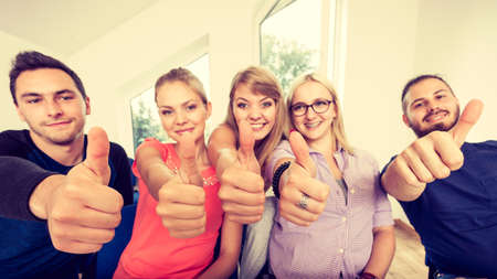 Education, friendship, success and teenage concept. Team of friends college students giving thumb up gesture of approval an success with their handsの写真素材
