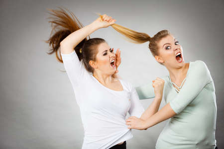Two agressive women having argue fight being mad at each other. Female violance concept.の写真素材