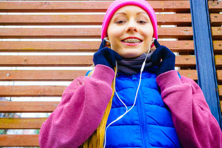 Outdoor sport exercises, sporty outfit ideas. Woman wearing warm sportswear training exercising and listening to music outside during autumn.のeditorial素材