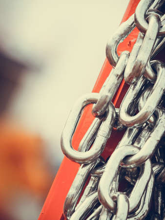 Abstract metal concept. Detailed closeup, lot of silver chains on red agriculture machineryの写真素材