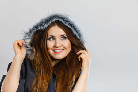 Happy woman wearing dark poncho coat with furry hood. Winter fashion, trendy clothing outfits concept.の写真素材