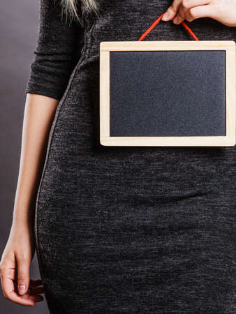Tummy belly problems, pain, digestion, constipation concept. Woman holding blank black board on stomachの写真素材