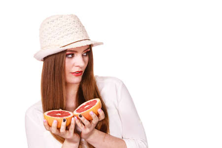 Woman attractive long hair girl colorful eyes makeup holding two halfs of grapefruit citrus fruit in hands. Healthy diet food. Summer vacation holidays conceptの写真素材