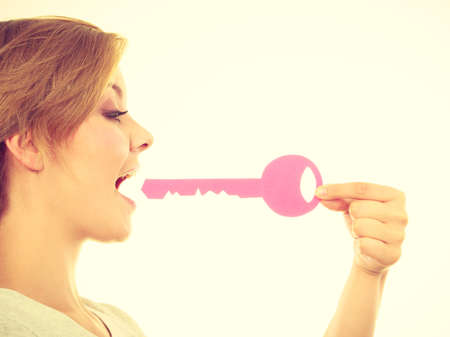 Language barrier, buying house concept. Teenage blonde girl biting big pink keyの写真素材