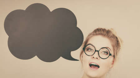 Student looking business woman wearing green shirt talking, black thinking bubble on grey background.の写真素材