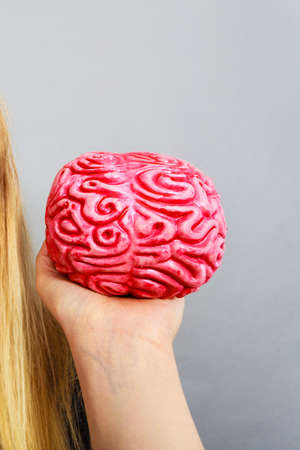 Weird blonde woman holding brain having something on mind, thinking of idea.