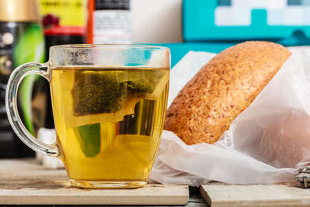 Meals in unusual surroundings concept. Glass with tea and bread in messy interiorの写真素材