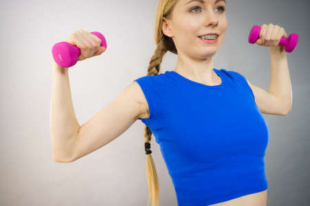 Teenage young woman working out at home with small light dumbbells. Training at home, being fit and...