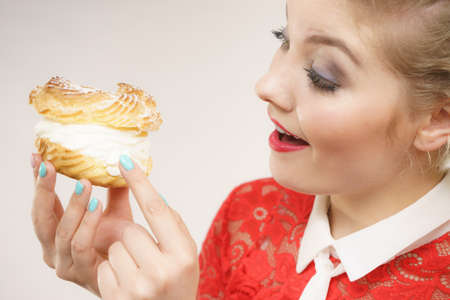 Sweet food and happiness concept. Funny joyful blonde woman holding yummy choux puff cake with...