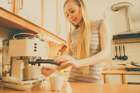 Woman in kitchen making hot drink coffee from machine. Barista at home.の写真素材