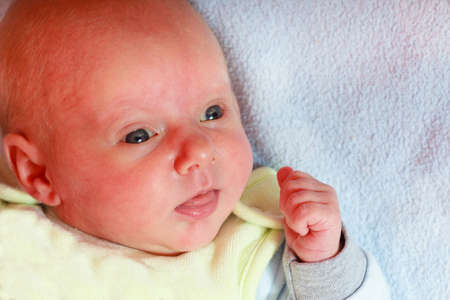 Infant care, beauty of childhood concept. Little newborn baby lying calmly in bed surrounded with...