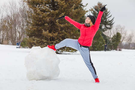 Outdoor recreation concept. Woman wearing warm sportswear playing on snow during winter time.の写真素材