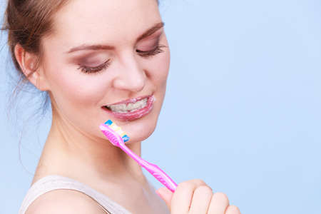 Woman brushing cleaning teeth. Girl with toothbrush. Oral hygiene. Blue backgroundのeditorial素材