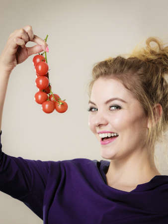 Organic vegetables and food concept. Happy positive smiling woman holding fresh cherry tomatoesの写真素材