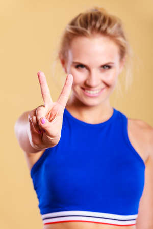 Sport, exercising and diet concept. Woman relaxing after doing sports. Fitness female in sportswear showing victory sign smilingの写真素材