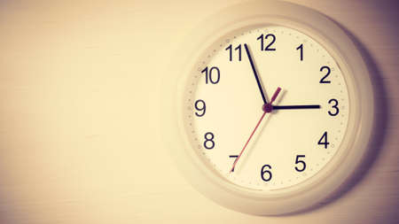 Clock hanging on wall ticking showing three hours