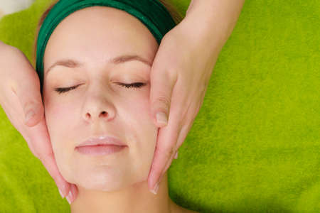 Spa relaxation, skincare, healthy pleasure concept. Woman lying with closed eyes having relaxing face massageのeditorial素材