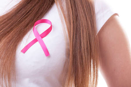 Healthcare, medicine and breast cancer awareness concept - Closeup of pink badge ribbon on woman chest to support breast cancer causeのeditorial素材