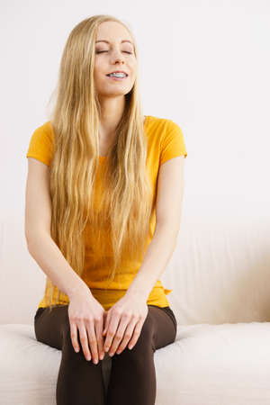 Happy woman with long blonde hair sitting and relaxing with closed eyes, meditate or thinking.の写真素材