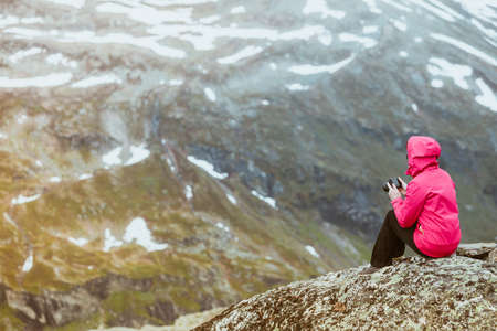 Tourism vacation and travel. Female tourist taking photo with camera, enjoying mountains landscape from Dalsnibba viewpoint, Norway Scandinavia.の写真素材