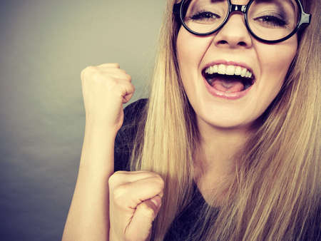 Closeup of weirdo woman face wearing big nerd geek eyeglasses having happy face expression, success or finding problem solution.の写真素材