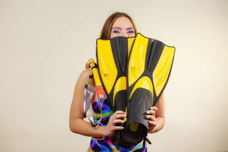 Woman wearing swimsuit with mask tuba, flippers, snorkel having fun studio shot on grey. Happy joyful girl dreaming about summer vacation. Snorkeling swimming conceptの写真素材