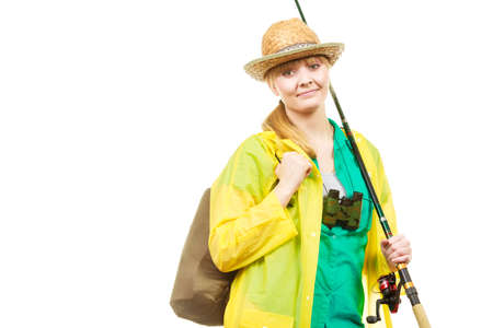 Fishery, spinning equipment, angling sport, activity concept. Woman wearing raincoat holding fishing rod and binoculars, ready for adventure.の写真素材