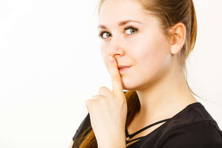 Woman showing silence shh gesture with finger close to mouth asking for being quiet