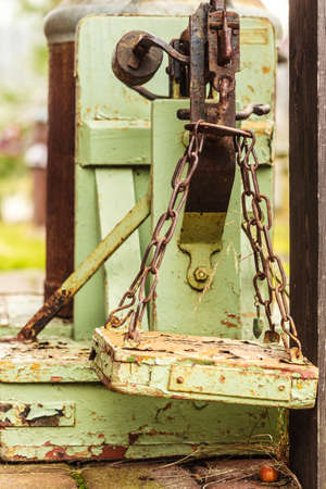 Vintage, antique objects concept. Old fashioned rotten green wooden weighing machine in sunlightの写真素材