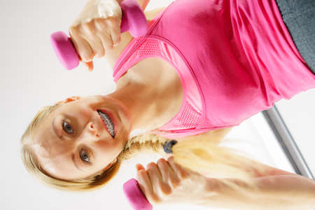 Teenage young woman working out at home with small light dumbbells. Training at home, being fit and...