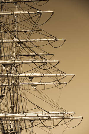 Detailed closeup of mast rigging top on sail boat during cruise, shot on dark sepia sky. Marine...