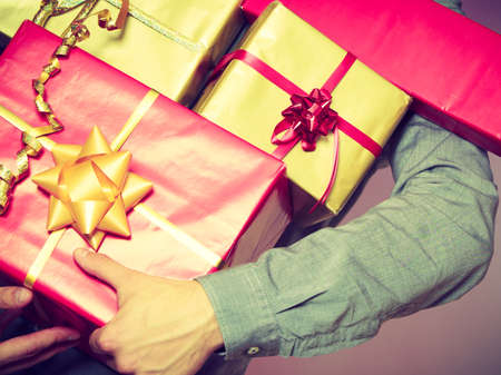 Holiday, xmas winter time season and special occasion. Closeup of male hands holding a lot of presents gifts boxesの写真素材