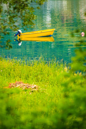 Little moored yellow boat on water sea or lake surfaceの写真素材