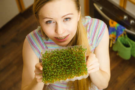 Happy woman holding green cuckooflower cress grown on cotton. Easter season decorations and food.の写真素材