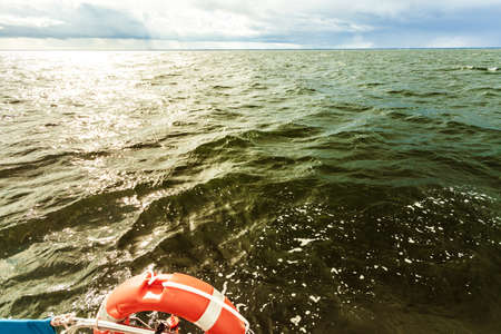 Water traveling, adventure concept. Sea view from yacht, lifebuoy close up, calm water, sunny weather, sky with many clouds.の写真素材