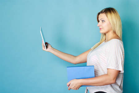 Modern education, devices for reading books, learning choice concept. Blonde woman choosing between...