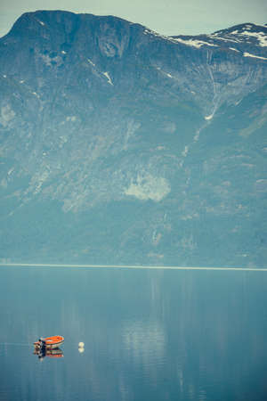 Little moored boat on blue water surface, fjord mountains landscape, Norway Europeの写真素材