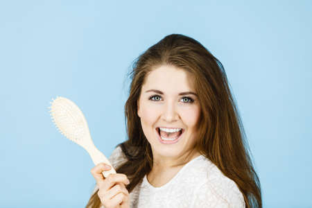Haircare and morning hairstyling concept. Happy woman brushing her long dark brown hair