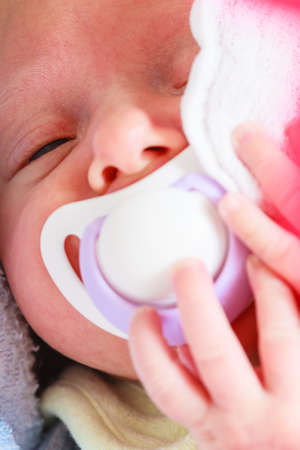 Infant care, beauty of childhood concept. Little newborn baby sleeping calmly in bed with teat in mouth.の写真素材