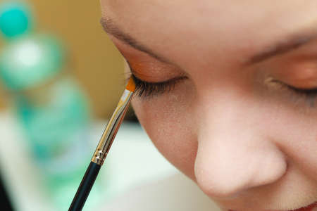 Visage concept. Close up woman getting make up on eyelids. Applying eyeshadow with brush, closed eyes.の写真素材