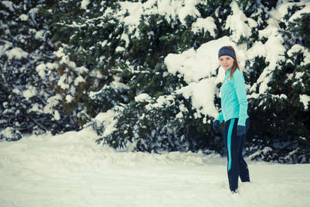 Girl wearing sportswear, trees in background. Winter sports, outdoor fitness, workout, health concept.の写真素材