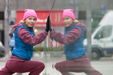 Sport and recreation. Fit slim sporty teen girl stretching warming up outdoor on city street. Woman...