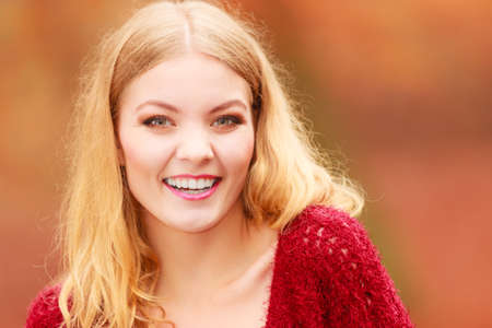 Portrait of stunning pretty smiling fashionable woman in fall forest park. Happy gorgeous young girl in maroon sweater pullover. Autumn winter fashion.の写真素材